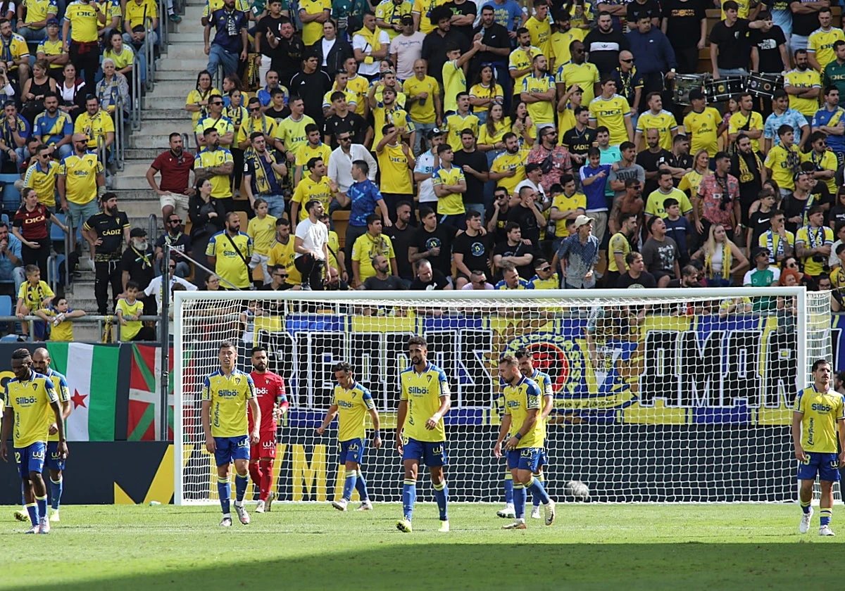 Jugadores del Cádiz CF sobre el césped con su afición al fondo