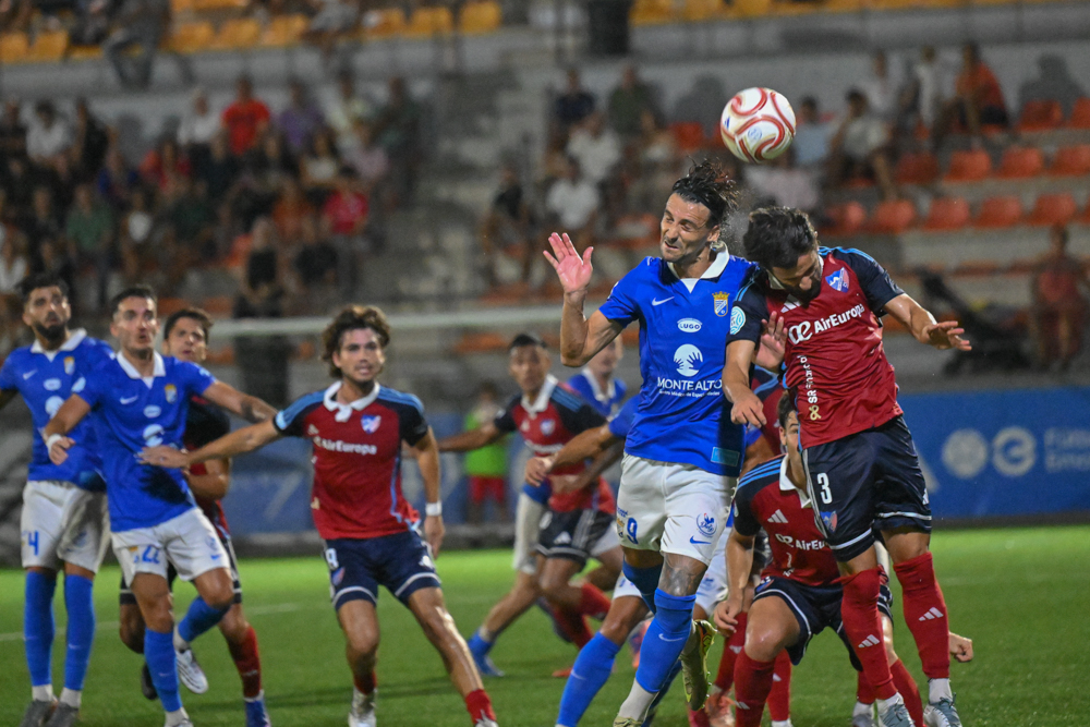 Xerez CD and Estepona players contest an aerial ball from a corner