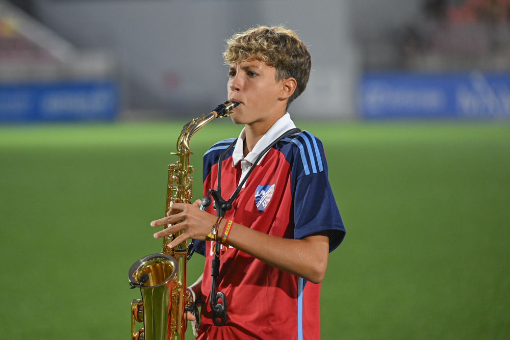 Hugo Castro, a CD Estepona academy player, performs the local anthem on his saxophone