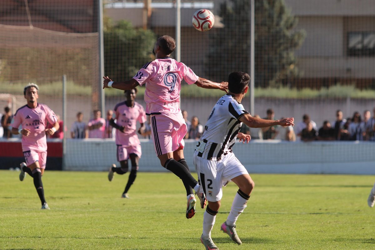 A Marbella FC player contests a header