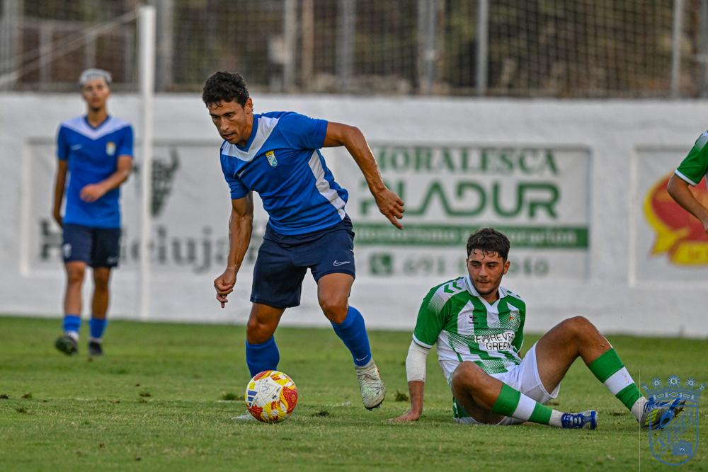 A Xerez CD player runs with the ball as a Real Betis C defender falls to the ground