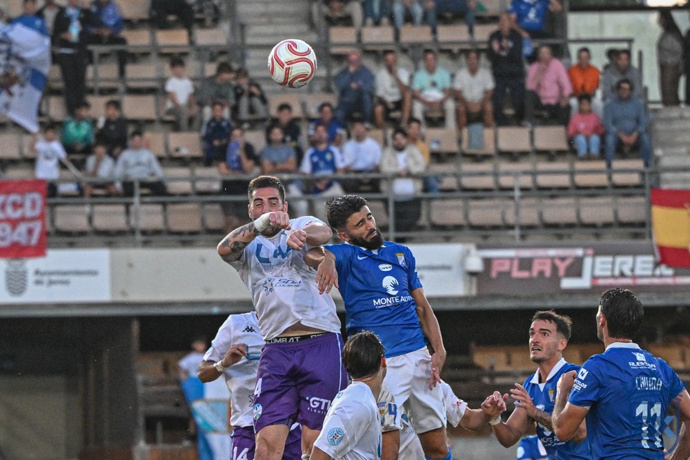 A Xerez CD player contests an aerial ball with a Ciudad de Lucena opponent inside the area at Chapín