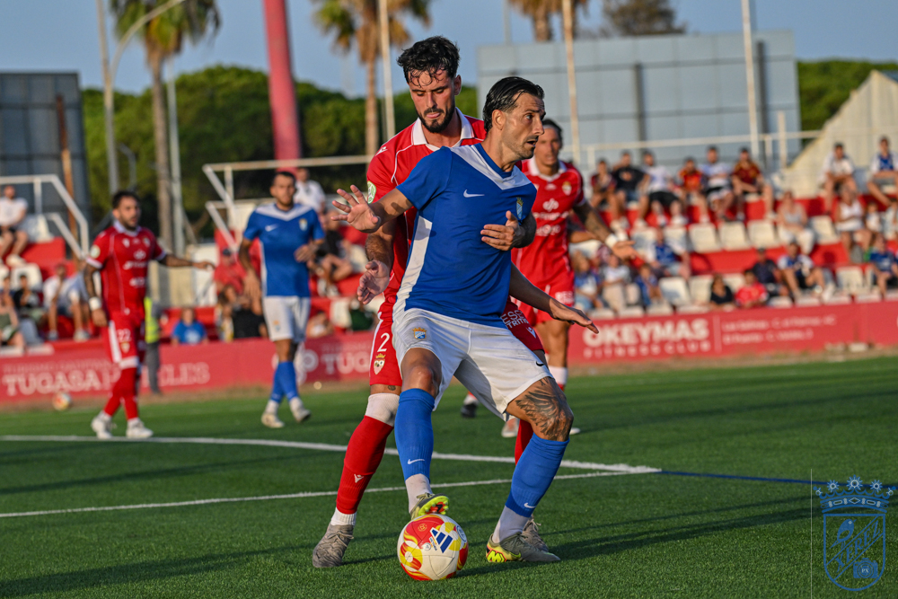 A Xerez CD player runs with the ball chased by a Racing Portuense defender